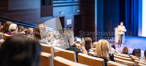 Image of Speaker giving a talk in conference hall at business event. Rear view of unrecognizable people in audience at the conference hall. Business and entrepreneurship concept.