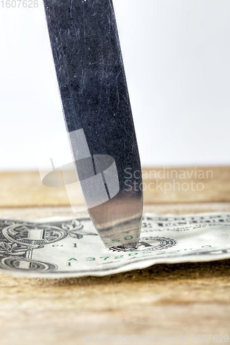 Image of one American dollar pierced with a knife