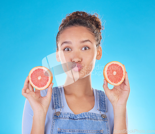 Image of Portrait, kiss and woman with grapefruit in studio isolated on a blue background. Face, fruit and person with food for healthy diet, nutrition or wellness, eating and vitamin c, benefits and vegan.