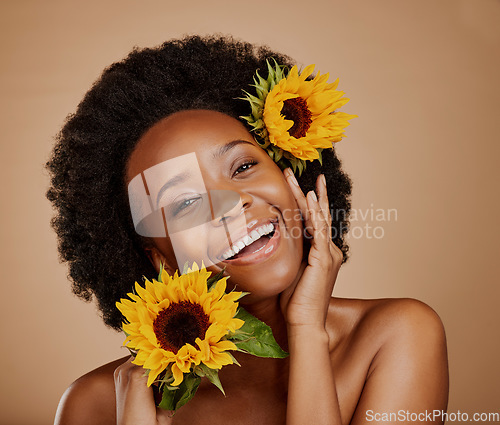 Image of Portrait, aesthetic and sunflower with a model black woman in studio on brown background for beauty. Face, skincare or natural cosmetics and a happy young female person with a flower in her afro hair