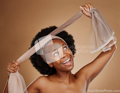 Image of Tie, afro or happy black woman with headband in studio for beauty, cosmetics or wellness on brown background. Model, smile or excited African girl with scarf for hair care, hairstyle or self love