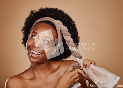 Image of Happy, afro or black woman with headband thinking of change or beauty in studio on brown background. Tie, smile or thoughtful African girl model excited by haircare idea, scarf hairstyle or self love