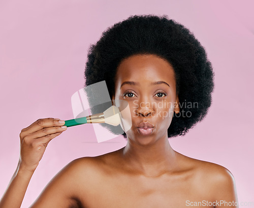 Image of Face, makeup and black woman with brush, kiss and beauty in studio isolated on a pink background. Portrait, facial cosmetics and African model apply foundation, powder and wellness for skincare pout.