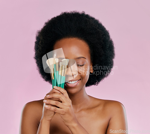 Image of Face, makeup and black woman with brushes, eyes closed and smile in studio isolated on a pink background. Skincare, facial cosmetics and African model with tools for foundation, powder and beauty.