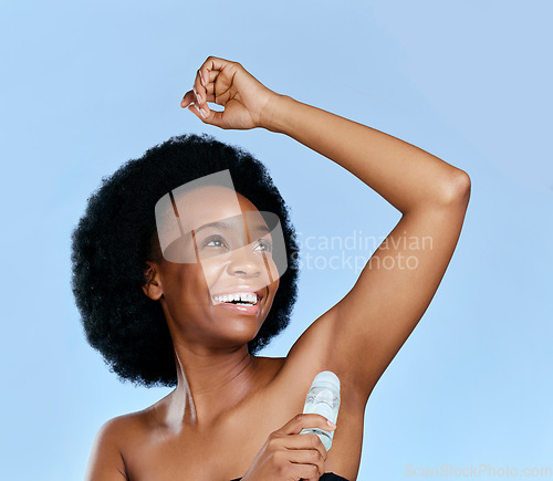 Image of Happy, deodorant and armpit of black woman for wellness in studio isolated on a blue background. Smile, underarm and African model with roll on product for cosmetics, thinking and healthy fresh scent