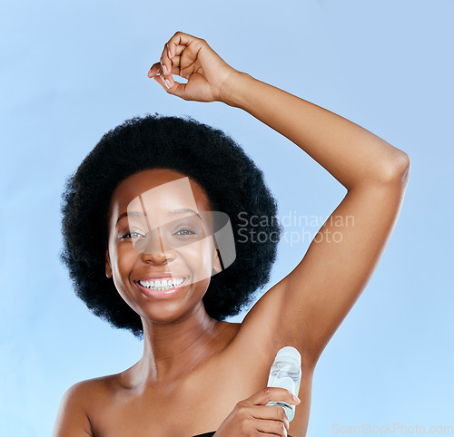 Image of Face, deodorant and armpit of black woman in studio isolated on a blue background. Portrait, underarm and happy model with roll on product for cosmetics, cleaning and hygiene, wellness or fresh scent