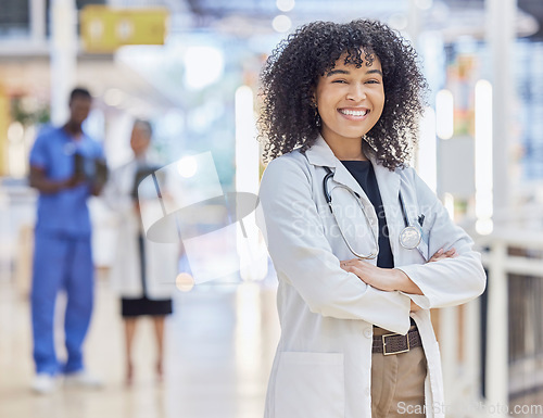 Image of Portrait, happy doctor and confident woman in hospital for healthcare. Face, arms crossed and African medical professional, surgeon or physician with smile, wellness and pride for career with bokeh.