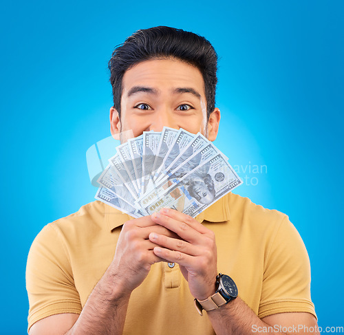 Image of Cash, fan and man with wow face isolated on blue, studio background for winning, money surprise or financial success. Lottery, finance secret and asian person winning, bonus and cashback in portrait