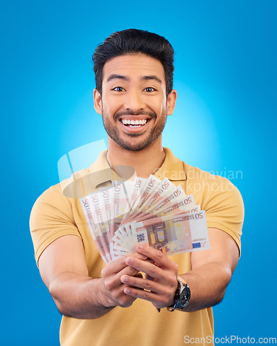 Image of Money, portrait and young man or winner with bonus, financial success and winning, cashback prize or lottery. Happy Asian person with savings, cash and investment isolated on studio blue background