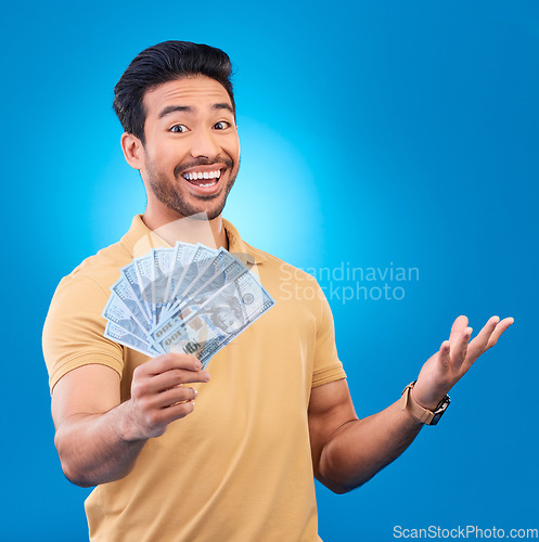Image of Money, studio and portrait of happy man excited for dollar bills, reward or bonus cash salary, giveaway or prize. Financial freedom, winner or person smile for income, revenue or blue background win