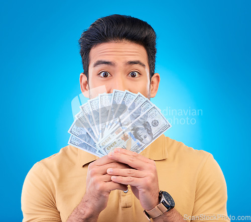 Image of Money, shocked face and man with financial surprise, winning or savings mistake isolated on blue, studio background. Lottery, finance secret and asian person gambling, bonus and cashback in portrait