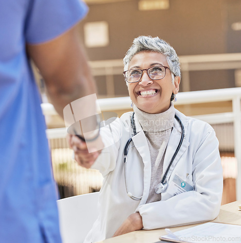 Image of Senior doctor, handshake and introduction, thank you and congratulations, smile and gesture with health. Welcome, communication and support in medicine, female medical professional and shaking hands