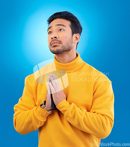 Image of Peace, man with hand gesture and praying against a blue background for worship. Thank you or faith, spiritual growth or meditation and young male person with emoji hands sign for religion in studio