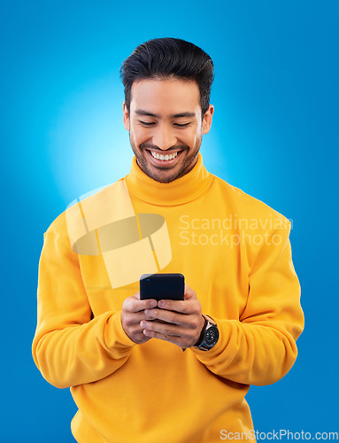 Image of Phone, happy and young man or student for social media, college feedback or news, email and online chat. Networking, search and asian person for university info on mobile and studio, blue background