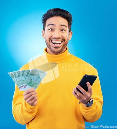 Image of Winner, money and portrait of Asian man with phone in studio for online bonus, competition and lottery. Success, finance and male person on blue background with cash for promotion, winning and deal