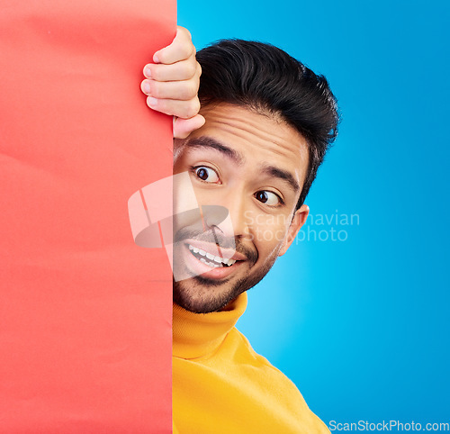 Image of Surprise, peeking and young man in studio with a wow, omg or wtf facial expression by a board with mockup. Happy, shock and male model with sneaky face by poster with mock up space by blue background