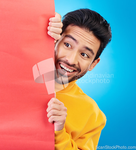 Image of Shock, hide and young man with billboard with wow, omg or wtf facial expression in studio with mockup. Happy, surprise and male model with sneaky face by poster with mock up space by blue background.