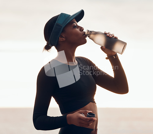 Image of Drinking water, fitness and black woman by ocean for exercise, marathon training and running. Sports, hydration and female person with liquid in bottle for thirst, cardio workout and body wellness