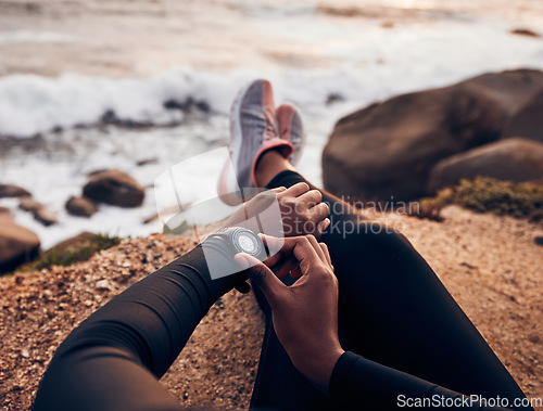 Image of Relax, check and smart watch with hand of woman on rock for running, fitness tracker and heart rate. Workout, exercise and goal with closeup of female runner at beach for monitor, goals and time