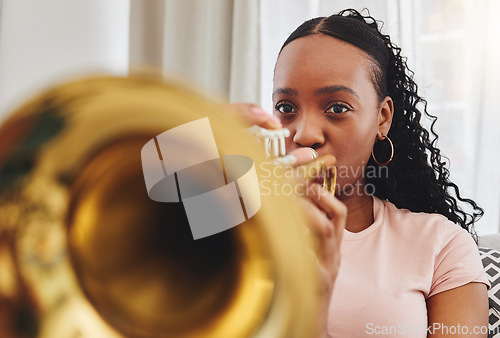 Image of Music, art and woman in home with trumpet, performance and band practice for orchestra concert in living room. Sound, creativity and jazz culture, African musician on sofa with musical instrument.