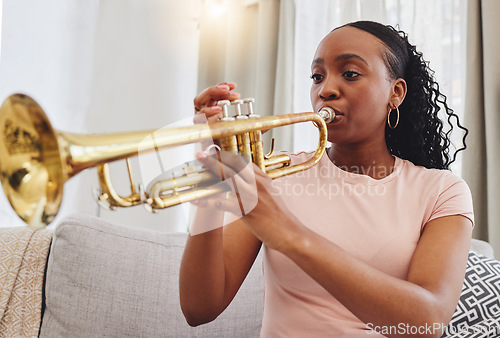 Image of Music, sofa and woman in home with trumpet, sound and band practice for orchestra concert in living room. Art, creativity and jazz culture, African musician on couch in performance and musical talent