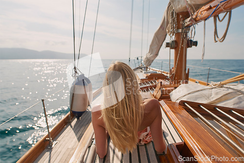 Image of Back, travel and a woman on a boat for a luxury cruise at sea during summer for a vacation or holiday. Water, view and horizon with a female tourist or traveler sitting on a yacht in the ocean