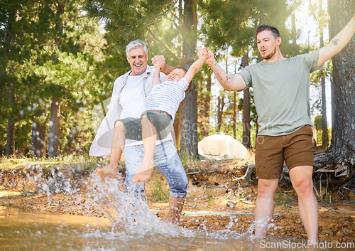 Image of Hiking, grandfather and dad swinging a boy with a water splash in the forest while on a camping trip together. Children, adventure and a family walking over a river while in the woods or wilderness