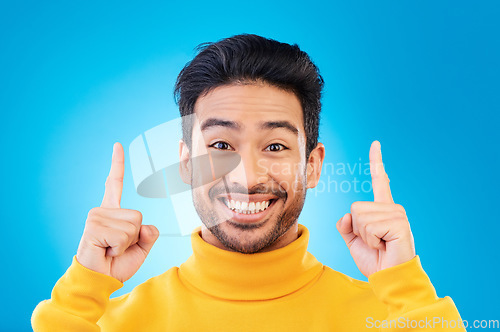 Image of Pointing up, excited and portrait of Asian man on blue background for news, announcement and information. Advertising, marketing and face of male person with hand gesture for promotion, deal and sale