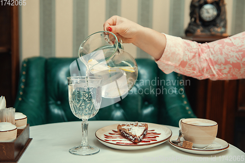 Image of Closeup photo of female hands is reaching out to cake