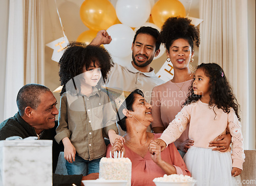 Image of Birthday, party and family with cake for grandmother in living room for event, celebration and social gathering. Happy, surprise and grandparents, parents and kids with dessert, snacks and presents