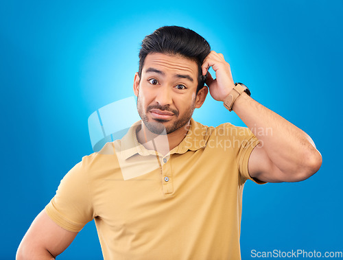 Image of Portrait, head scratch and man confused over question, doubt or uncertain about problem crisis, error or decision. Studio, face and Asian male person unsure about choice isolated on blue background