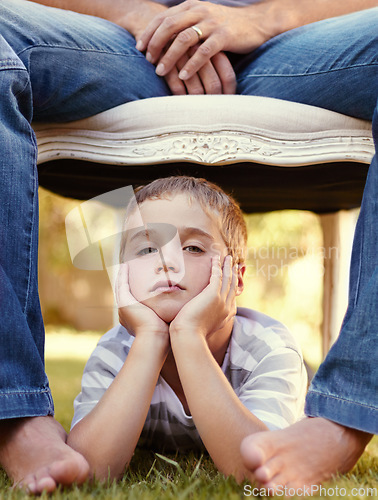 Image of Bored, face and portrait of child with parent lying on grass for bonding, support and love in outdoor park together. Care, chair and young kid with father or dad on vacation or holiday travel
