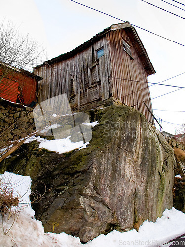 Image of Wooden, house and snow on a cliff in Norway in winter weather for housing and living. Snowing, frozen and wood cabin outdoors in a village in the Scandinavian or Europe countryside for lifestyle