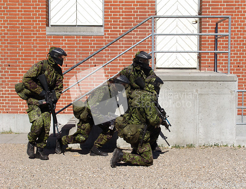 Image of Camouflage, soldier and training by building with weapon for fitness, exercise or challenge outdoor with gear. Military, people and hiding for target, mission or bootcamp with helmet for survival