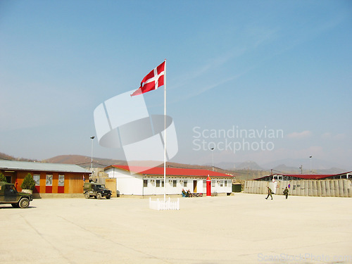 Image of Denmark, flag and building on landscape with blue sky for military training, bootcamp or government land. Army, base and people outdoor with soldier in countryside for national service and protection