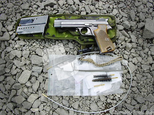 Image of Military, weapon and handgun with cleaning kit on ground outdoor for service, mission or protection of soldier. Pistol, sniper or gun for maintenance, danger or shooting on battlefield or operation