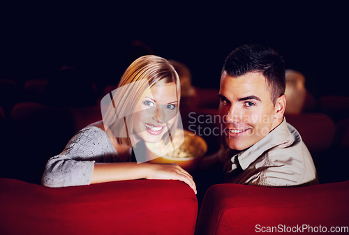 Image of Cinema, portrait and couple with popcorn on date, watching film or video on romantic night together. Movies, man and woman in theater with snacks, smile and sitting in auditorium to relax in audience