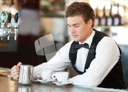 Image of Coffee, barista and young man waiter in cafe making a latte, espresso or cappuccino at an event. Hospitality, server and male butler preparing a warm beverage in a mug or cup by a bar in restaurant.