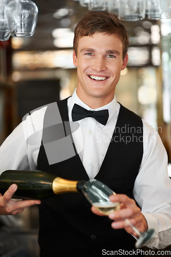 Image of Man, bartender and waiter with champagne at restaurant for happy hour, hospitality industry or customer service. Portrait of barman, server or catering employee smile, wine glass and alcohol bottle