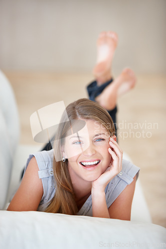 Image of Portrait, smile and relax with a woman on a sofa in the living room of her home on the weekend. Face, natural and a happy young person lying in her apartment for peace or wellness on a break