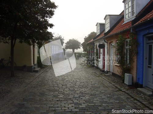 Image of Cottage, cobblestone street and village, travel and neighborhood in Denmark with landscape or background. Traditional, town and tourism with road, property or houses, architecture and countryside