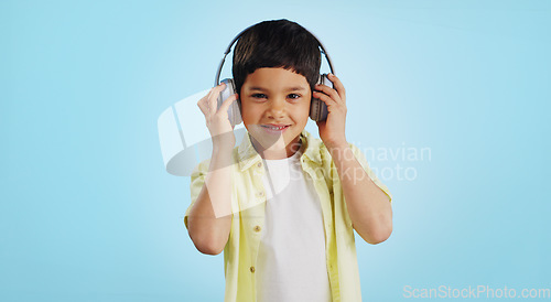 Image of Kid, dancing and listening to music in studio with smile on blue background in mockup for fun, promotion and summer. Youth, boy or person with headphones for app, streaming or game on social media