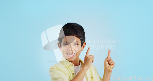Image of Kid, boy and smile while pointing in studio on blue background with mockup for announcement, offer or deal. Youth, happy and excited about notification on social media, online or digital marketing