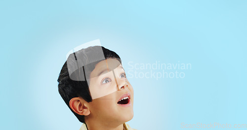 Image of Surprise, boy and child with decision, opportunity and fantasy on a blue studio background. Person, mockup space and happy kid looking up, future and announcement with shock, expression and emoji