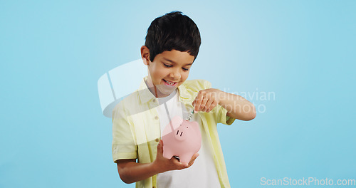 Image of Piggy bank, cash and child face with money, savings and cash planning in a studio, Happy, portrait and young boy with allowance and safe for bills, wealth and budget with blue background and smile