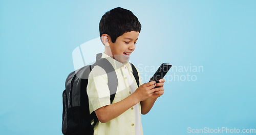 Image of School, phone or kid on social media in studio typing to chat, play mobile games or download app. Blue background, student or happy boy child reading notification for online education or tech search