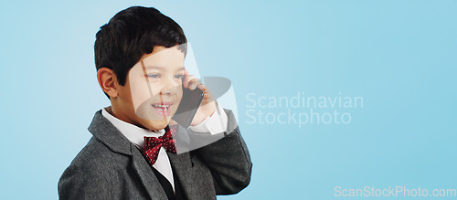 Image of Child, talking and boy with phone call in studio, blue background and mockup with telephone chat or conversation. Calling, kid and speaking with cellphone communication or discussion with mobile