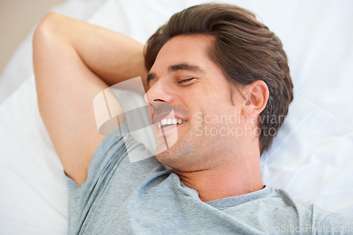 Image of Sleeping, smile and young man on a bed for resting, relaxing or calm and positive mindset in apartment. Happy, peaceful and male person from Australia taking nap on weekend in bedroom at modern home.