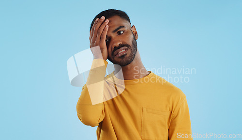 Image of Stress, fail and man in studio with facepalm emoji for stupid mistake or regret on blue background. Anxiety, oops and male model with disaster, crisis or fake news shame, frustrated and unhappy