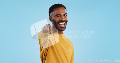 Image of Face, wink and man with hand pointing at you in studio with choice, selection or offer on blue background. Opportunity, offer and portrait of male model with emoji for join us, deal or invitation